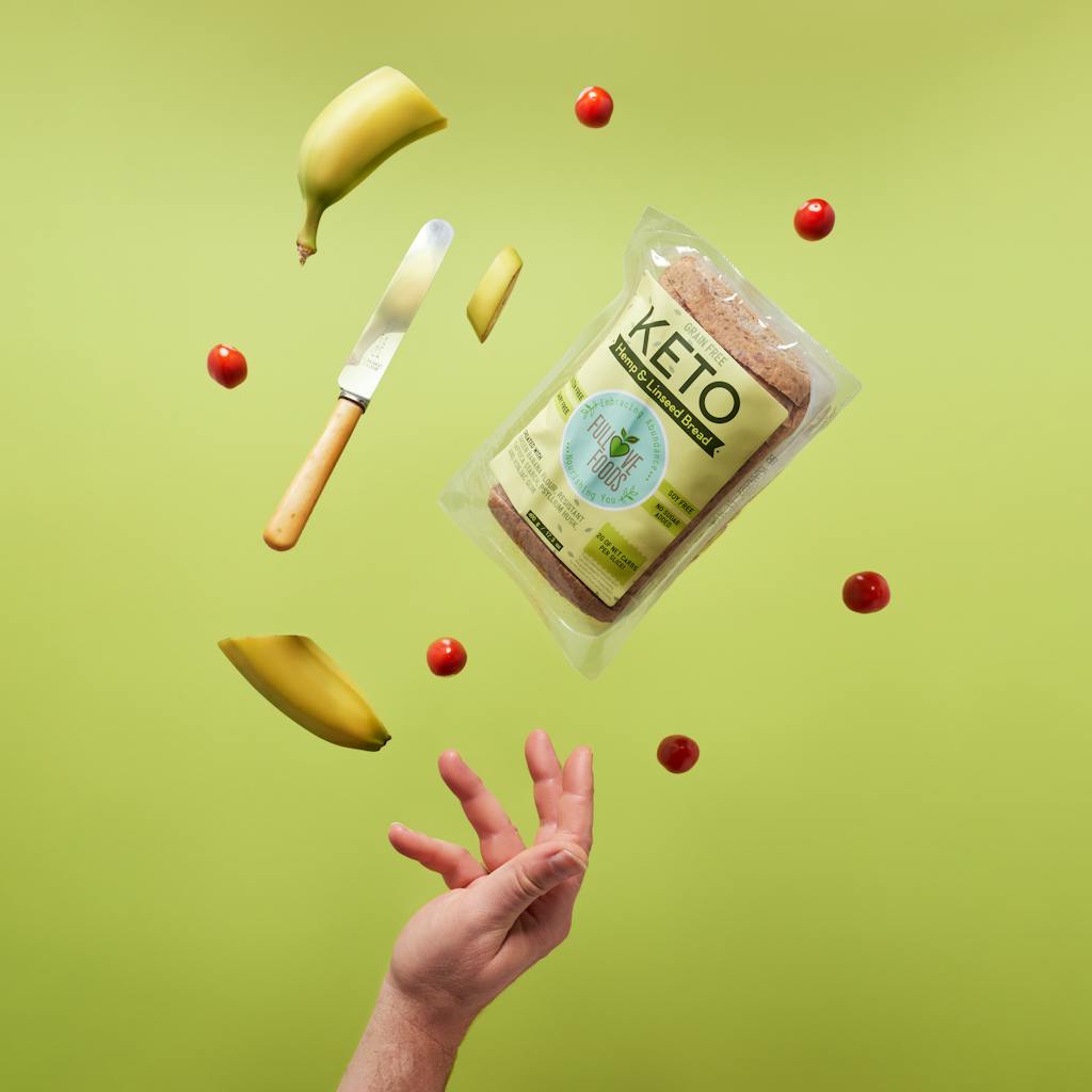 Pływający chleb keto z bananami, nożem i pomidorkami koktajlowymi na żywym tle.